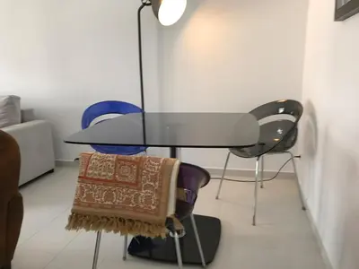 a glass table and chairs in a room with a couch at American Style Apt Pool & AC in Oulad Akkou