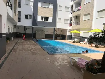 a swimming pool in a building with people in it at American Style Apt Pool & AC in Oulad Akkou