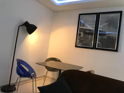 a room with a table and a lamp and a table and chairs at American Style Apt Pool & AC in Oulad Akkou