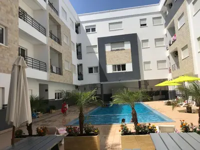 an apartment building with a swimming pool in a courtyard at American Style Apt Pool & AC in Oulad Akkou