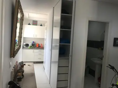 a kitchen with white cabinets and a sink and a mirror at American Style Apt Pool & AC in Oulad Akkou