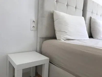 a white bed with a white pillow and a side table at Spacious Apartment PoolAir Conditioning Terrace in Oulad Akkou