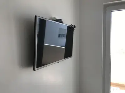a flat screen tv hanging on a wall at Spacious Apartment PoolAir Conditioning Terrace in Oulad Akkou