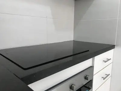 a black counter top in a white kitchen at Spacious Apartment PoolAir Conditioning Terrace in Oulad Akkou