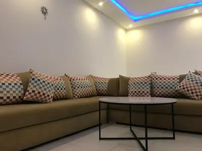 a brown couch with pillows on it with a table at Cozy Apartment Near the Beach & Public Pool in Oulad Akkou