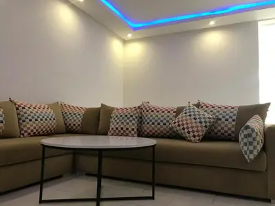 a couch with pillows and a table in a room at Cozy Apartment Near the Beach & Public Pool in Oulad Akkou