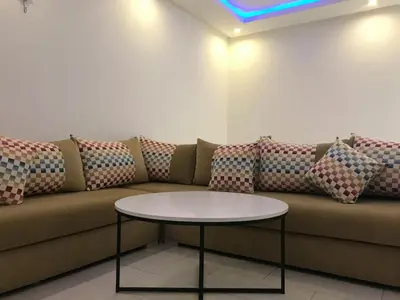 a couch with pillows and a table in a room at Cozy Apartment Near the Beach & Public Pool in Oulad Akkou
