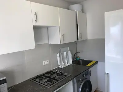 a kitchen with a stove top oven next to a washing machine at Cozy Apartment Near the Beach & Public Pool in Oulad Akkou