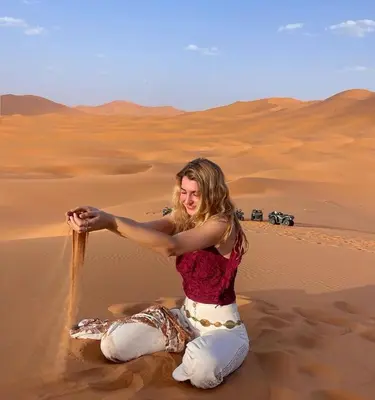 a woman sitting in the sand in the desert at Tranquil gem luxury camp in Merzouga
