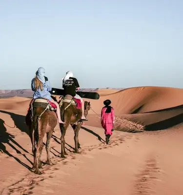 two people riding on camels in the desert at Tranquil gem luxury camp in Merzouga