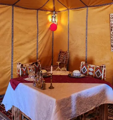 a room with a table in a tent at Tranquil gem luxury camp in Merzouga
