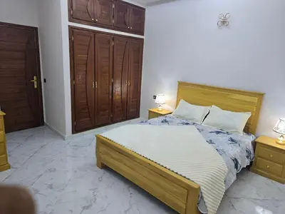 a bedroom with a bed with a wooden headboard at joli appartement à petit prix in Meknès