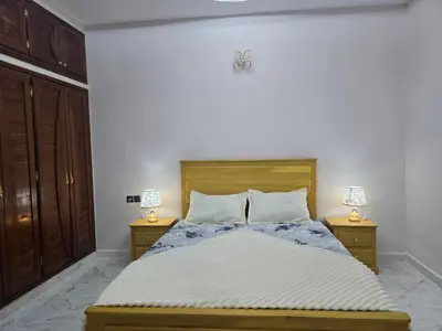 a bedroom with a bed with two lamps on two tables at joli appartement à petit prix in Meknès