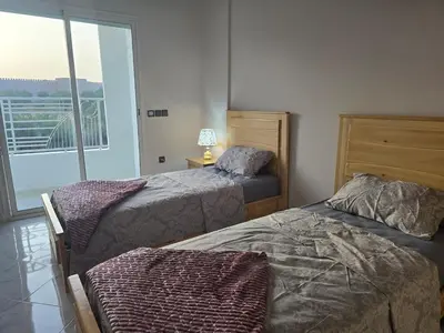 a bedroom with two beds and a balcony at joli appartement à petit prix in Meknès