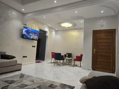 a living room with a couch and a table with chairs at joli appartement à petit prix in Meknès