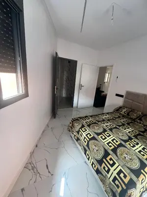 a bedroom with a bed with a comforter and a window at شقق الشرايبي للعائلات فقط in Beni Mellal