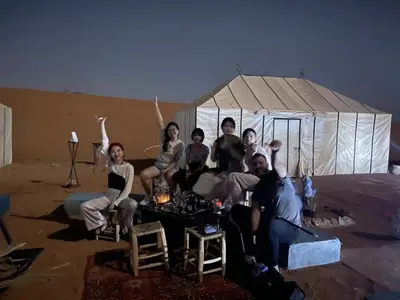a group of people sitting in front of a tent at Merzouga Paradise Luxury Camp in Merzouga