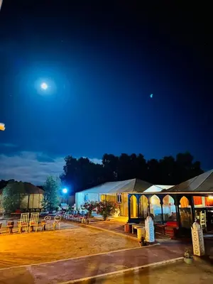 a group of tables and a building at night at Merzouga Desert Experience Camp-Erg Chebbi Sunset & Camel Ride in Merzouga