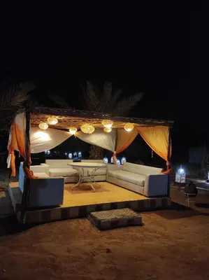 a white couch under a tent at night at Merzouga Desert Experience Camp-Erg Chebbi Sunset & Camel Ride in Merzouga