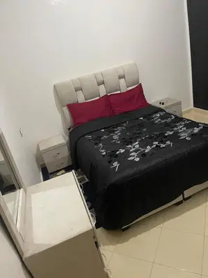 a large bed with a black blanket and red pillows at Bel Appartement à louer à Fès in Fès