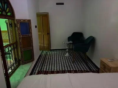 a bedroom with a bed and a chair and a door at M & S Guest House in Fès