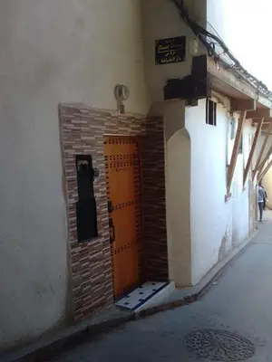 an orange door on the side of a brick building at M & S Guest House in Fès