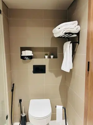 a bathroom with a toilet and towels on shelves at Majestic apt Casa City Center in Oulad Akkou