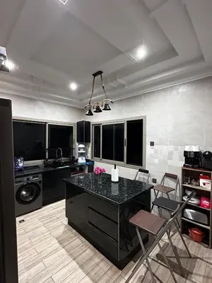 a kitchen with a black counter and chairs in it at Villa Adam in Meknès