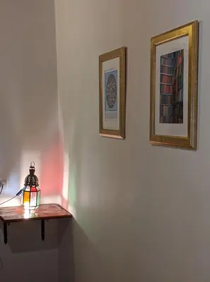 a lamp on a shelf with two pictures on a wall at Dar Omar in Fès