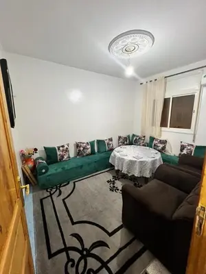 a living room with a green couch and a table at Au centre de la ville pour les familles seulement in Khenifra