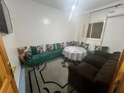 a living room with a green couch and a table at Au centre de la ville pour les familles seulement in Khenifra