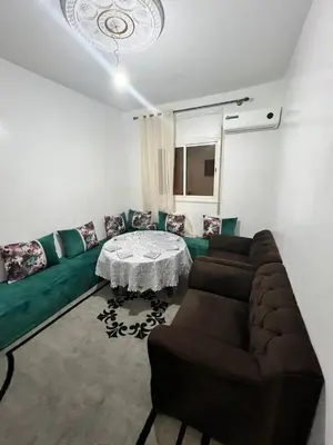 a living room with a green couch and a table at Au centre de la ville pour les familles seulement in Khenifra