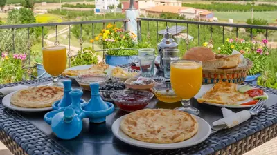 a table topped with plates of food and glasses of orange juice at Gîte Forest Tagroumet traditionel in Ifrane