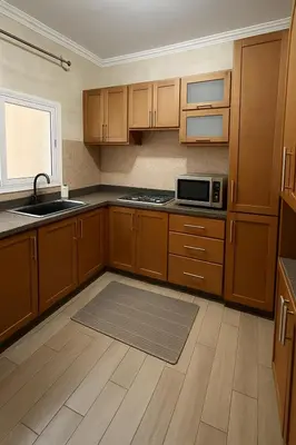 a kitchen with wooden cabinets and a sink and a microwave at Appartement Pam Pam in Fès