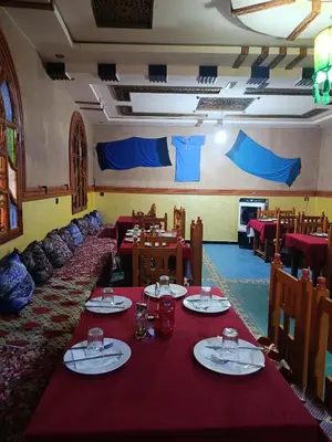 a dining room with tables and chairs with red table cloth at Africa Hollywood in Aït Ben Haddou