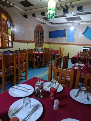 a dining room with tables and chairs with red table cloth at Africa Hollywood in Aït Ben Haddou