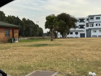 a field with two trees and a building at Luxurious apartment in Oud Fes golf city in Fès