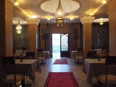 a dining room with tables and chairs and a large window at Palm Dades in Boumalne