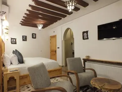 a bedroom with a bed and two chairs and a tv at Palm Dades in Boumalne