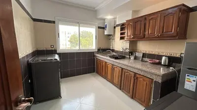 a kitchen with wooden cabinets and a black refrigerator at Luxurious apartment at a low price in Meknès