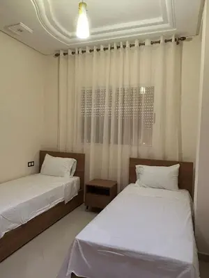 two beds in a room with white curtains at Luxurious apartment at a low price in Meknès