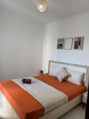 a bedroom with a bed with orange and white sheets at Fès comfort stay in Fès