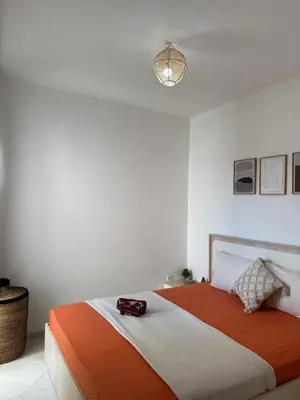 a bedroom with a bed with an orange and white blanket at Fès comfort stay in Fès