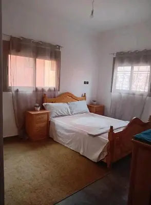 a bedroom with a large bed and two windows at Appartement familial, plein centre d'Azilal in Azilal