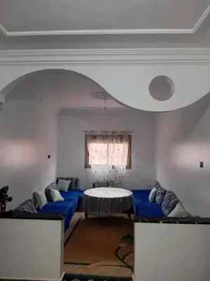 a living room with a blue couch and a table at Appartement familial, plein centre d'Azilal in Azilal