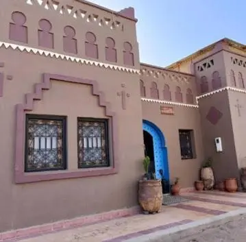 a large building with a blue door and a building at فندق حاسي لبيض in Hassilabied