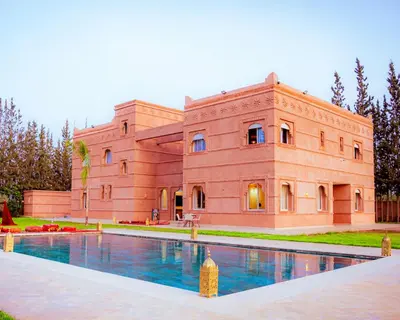 a large brick building with a swimming pool in front of it at Palais Dar Souhir in Sidi Bouzguia