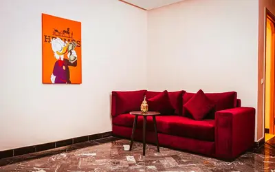 a red couch in a living room with a table at Palais Dar Souhir in Sidi Bouzguia