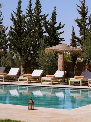 a swimming pool with lounge chairs and a umbrella at Palais Dar Souhir in Sidi Bouzguia