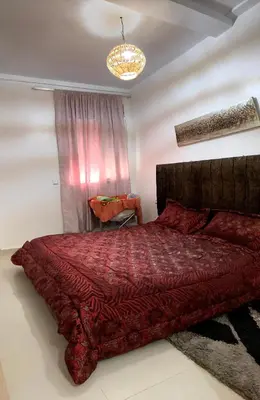 a bedroom with a large red bed with a chandelier at Chill unique apartment in Ifrane in Ifrane